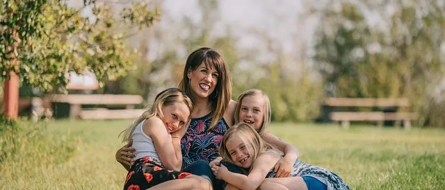 A mother and her three daughters laughing together outdoors